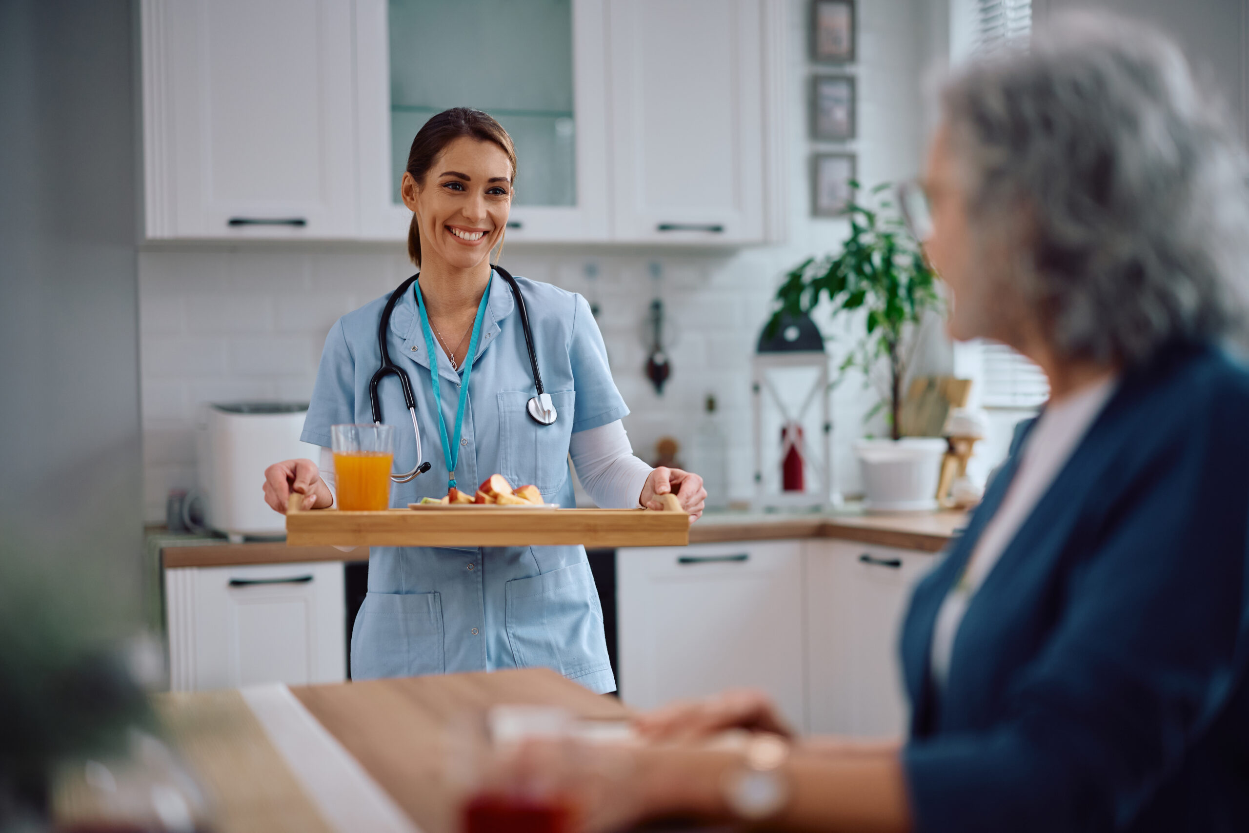nurse caregiver giving tray of food to senior for meal preparation in michigan ohio and florida